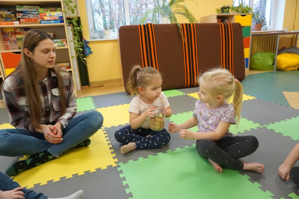  Dzieci siedzą i podają sobie słoik