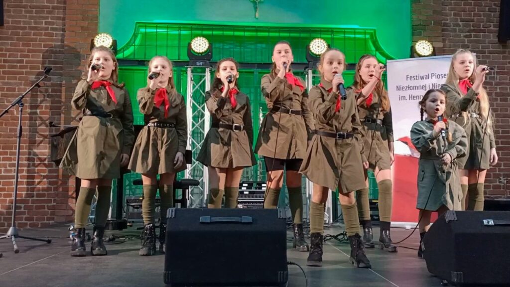 Na scenie dziewczynki śpiewają pieśni patriotyczne