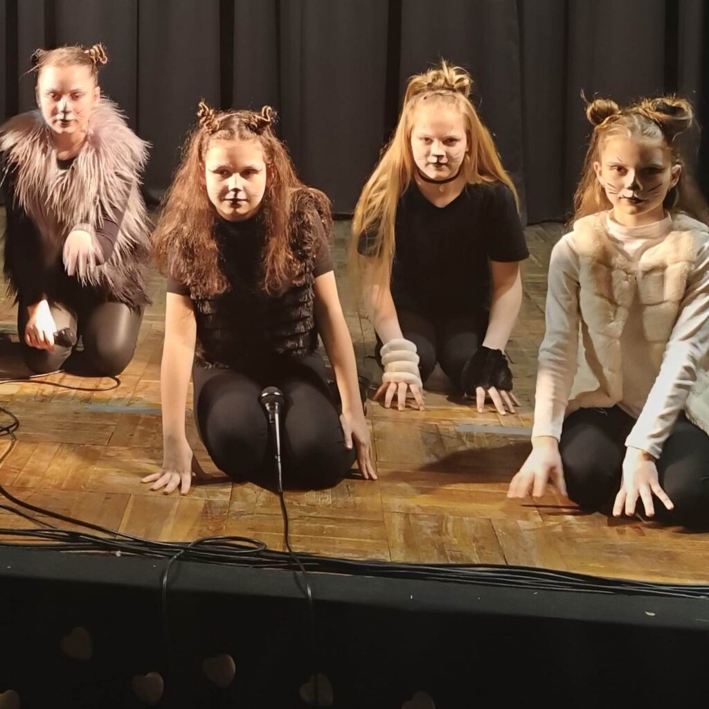 Dziewczynki tańczące na scenie przebrane za koty