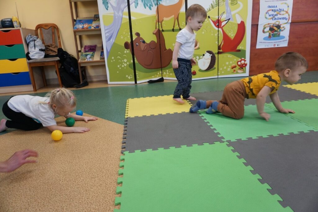  Dzieci dmuchają piłeczki leżąc na podłodze