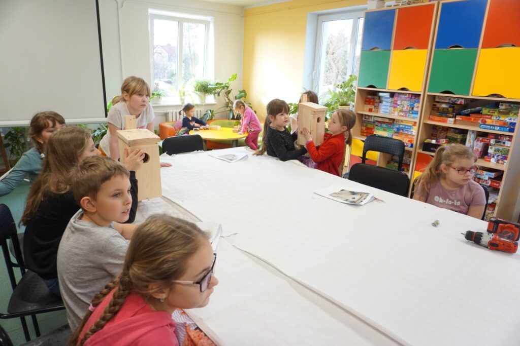 Dzieci siedząc przy stołach odpowiadają na pytania