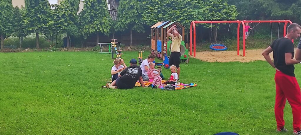 trawa, drzewa, rowery, ludzie siedzący na trawniku