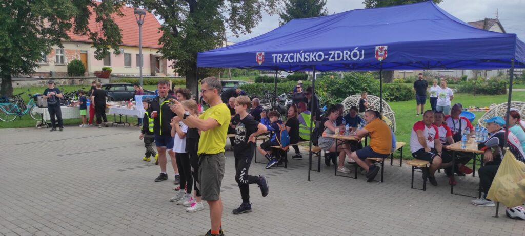 Ławki pod namiotem, świetlica wiejska, teren z kostki brukowej, rowerzyści przy posiłku