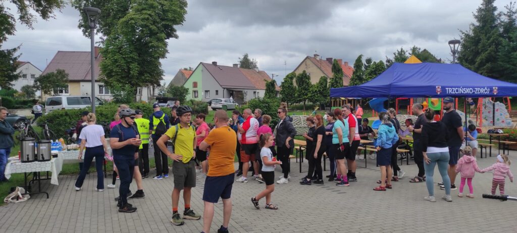 Ławki pod namiotem, świetlica wiejska, teren z kostki brukowej, rowerzyści przy posiłku