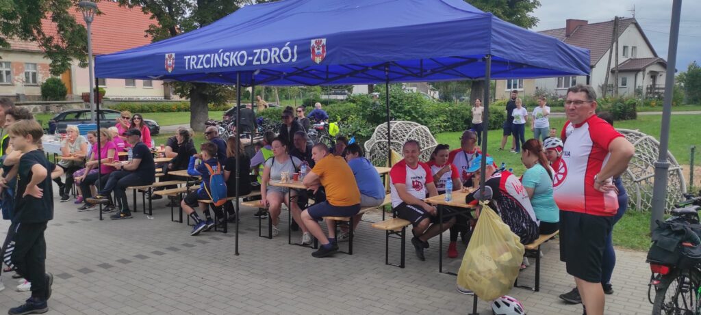 Ławki pod namiotem, świetlica wiejska, teren z kostki brukowej, rowerzyści przy posiłku