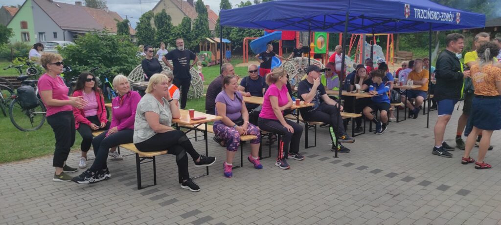 Ławki pod namiotem, świetlica wiejska, teren z kostki brukowej, rowerzyści przy posiłku