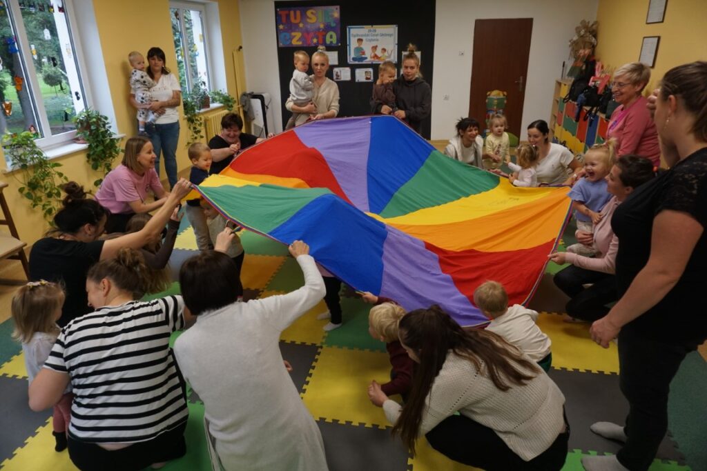 piłeczki kolorowe, kolorowa płachta, dzieci i opiekunowie podrzucają mata piłeczki