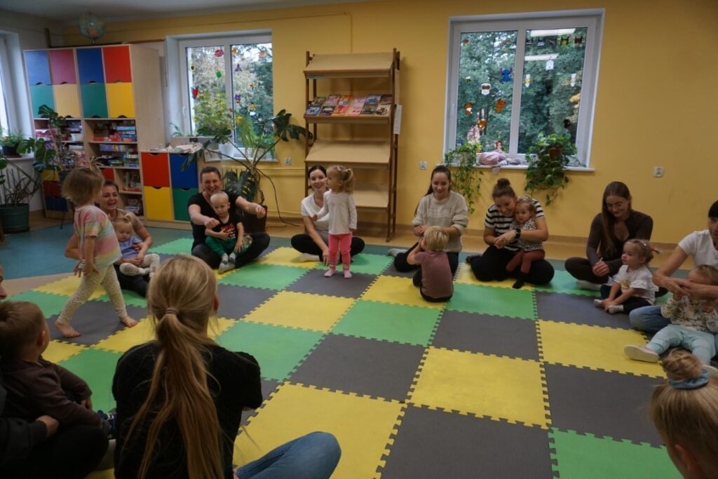 Dzieci, opiekunowie, siedzą na macie,