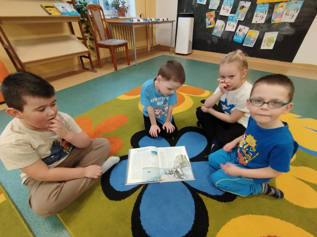 Dzieci z siedzące na dywanie z książeczką