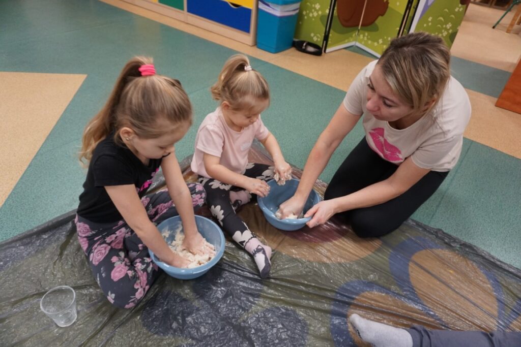 Dziecko siedzące na dywanie, mieszające masę solną w miseczce