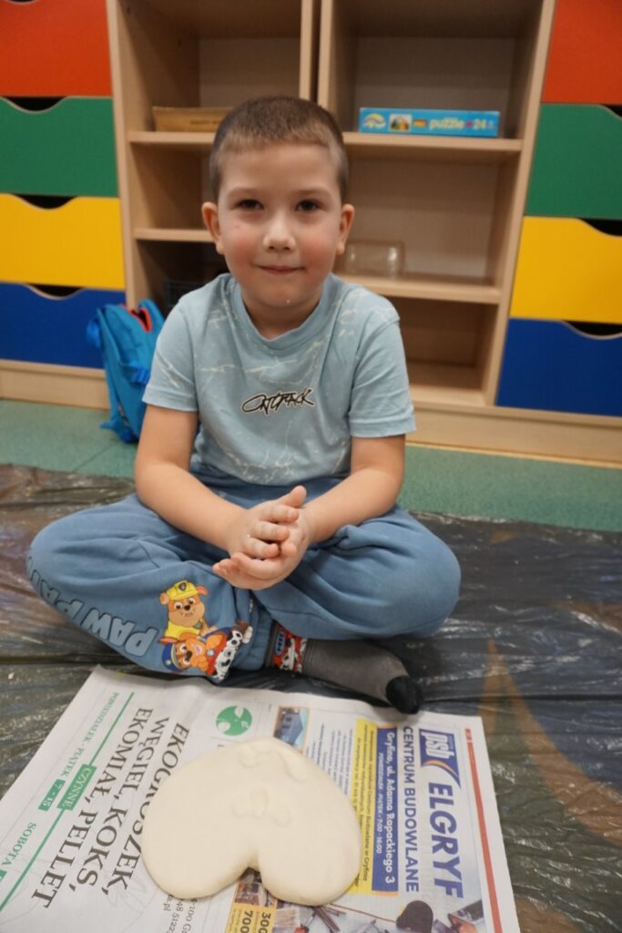 Dziecko siedzące na dywanie, obok serca wykonanego z masy solnej