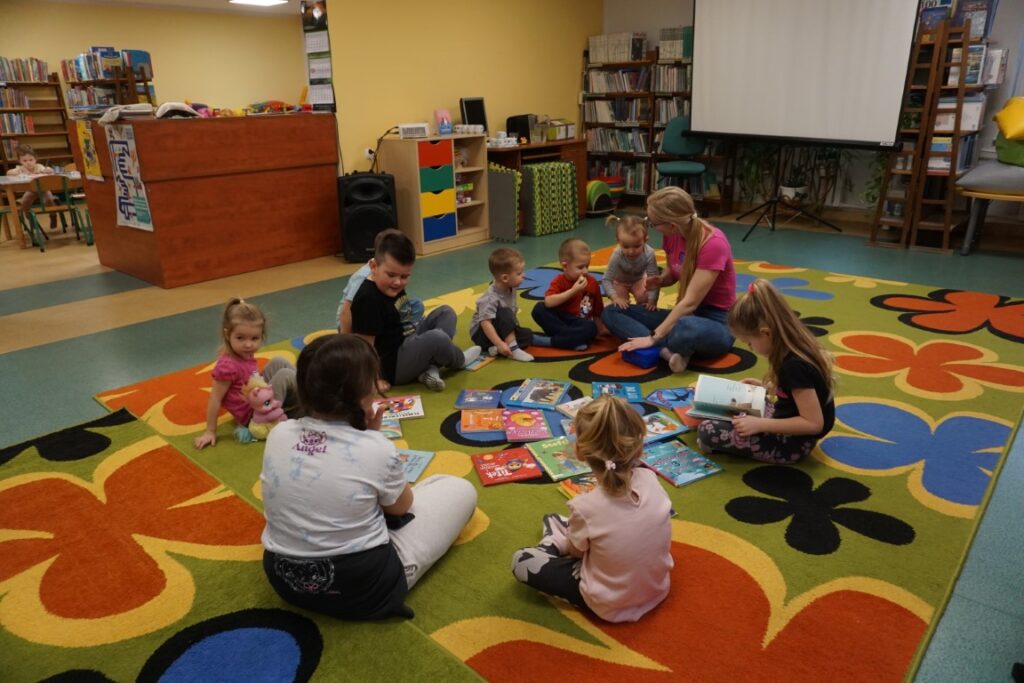 Dzieci siedzące na dywanie przeglądające bajeczki