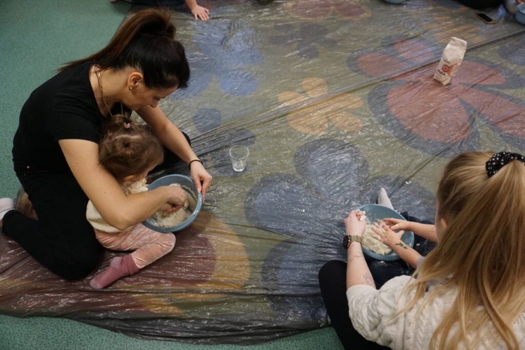 Dziecko siedzące na dywanie, mieszające masę solną w miseczce