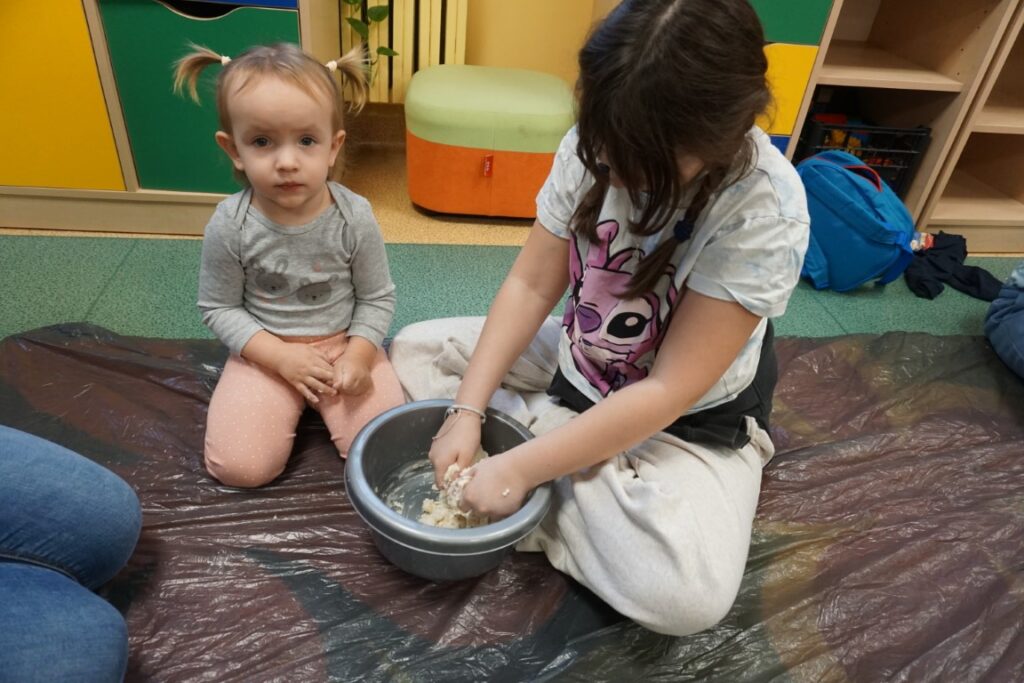 Dziecko siedzące na dywanie, mieszające masę solną w miseczce