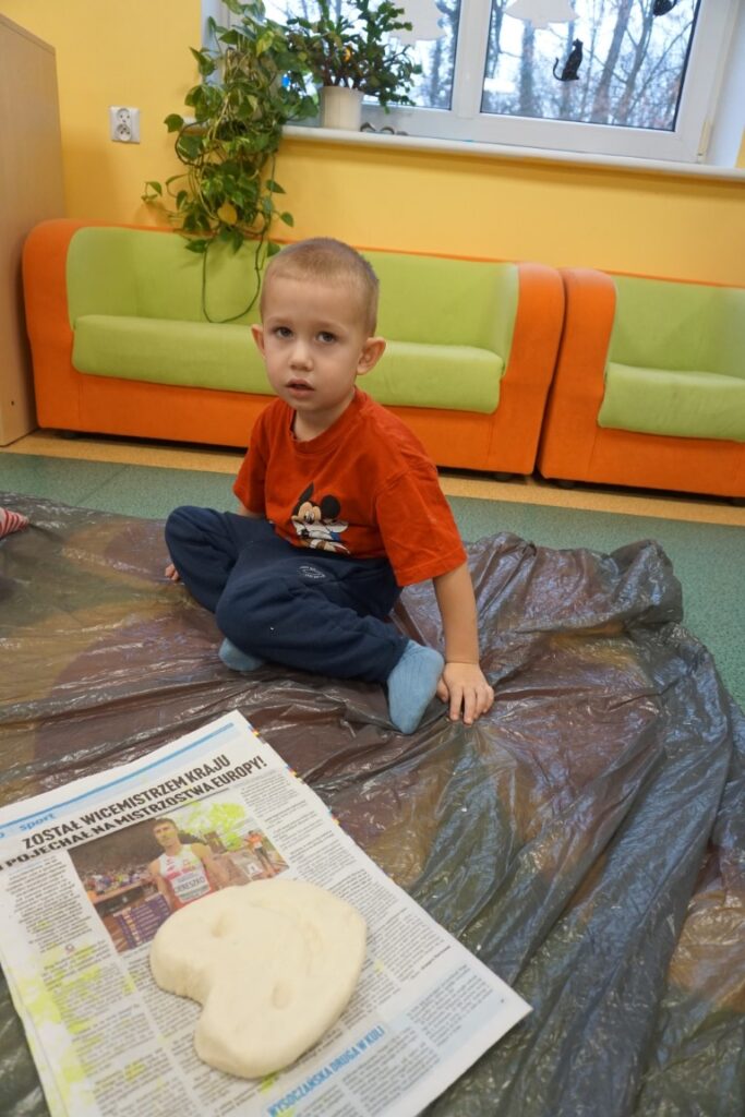 Dziecko siedzące na dywanie, obok serca wykonanego z masy solnej