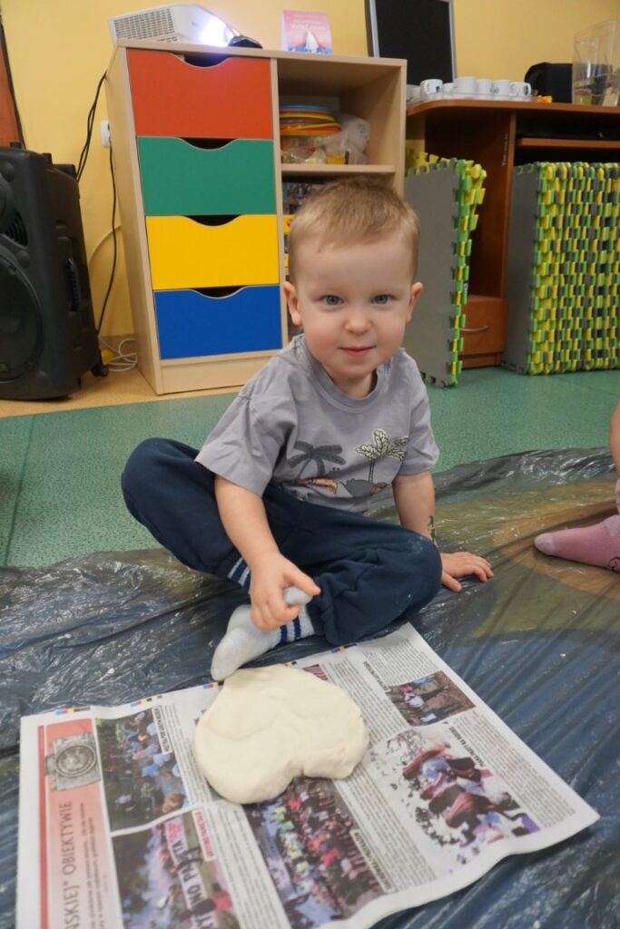 Dziecko siedzące na dywanie, obok serca wykonanego z masy solnej