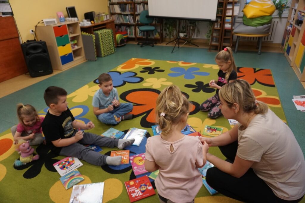 Dzieci siedzące na dywanie przeglądające bajeczki