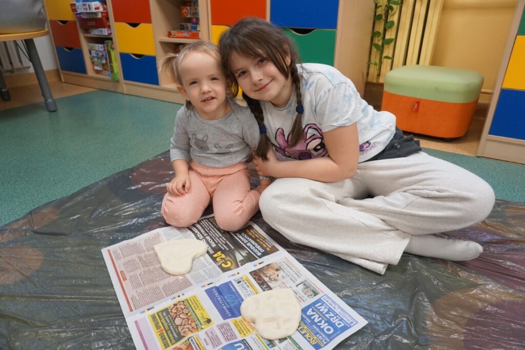 Dziecko siedzące na dywanie, obok serca wykonanego z masy solnej