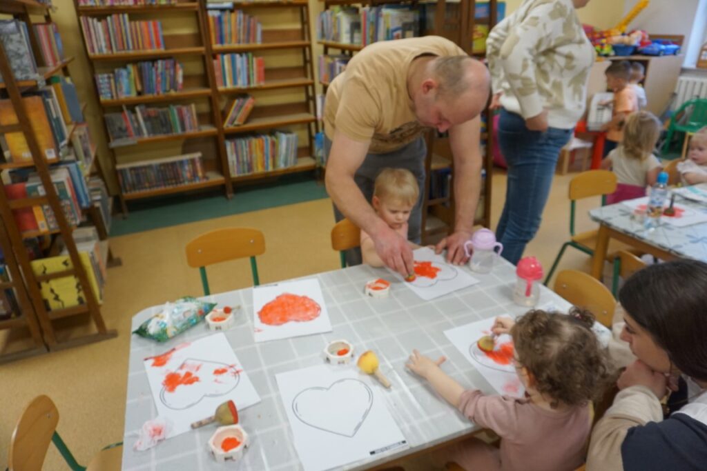 Dzieci przy stoliczkach malujące serca