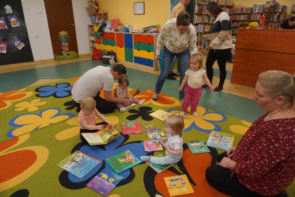 Dzieci i opiekunowie oglądające książeczki