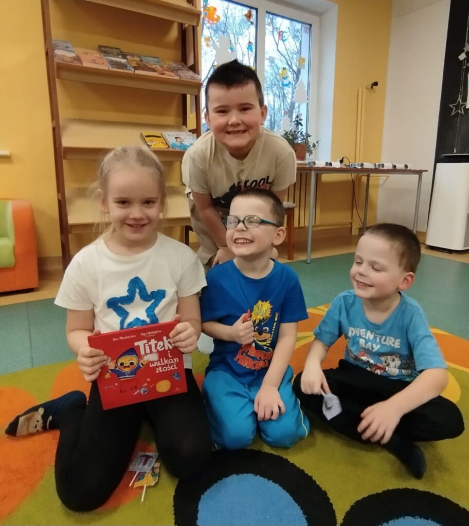 Dzieci z siedzące na dywanie z książeczką